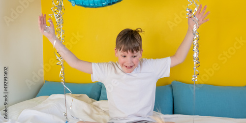 The inflatable figure 8 is in the hands of a contented happy boy. A boy in his room is playing with a supercharged eight on his birthday
