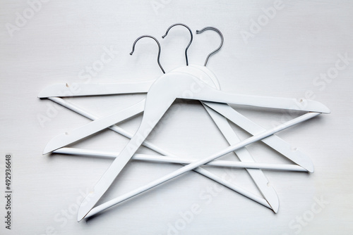 White wooden empty coat hangers with metal hook top view white wooden table background