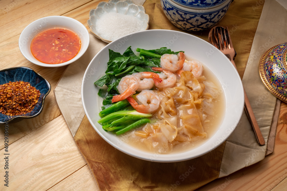 Wide Rice Noodles with Shrimp and kale in Gravy Sauce Served with condiments, chili powder , chili sauce and sugar. Asian food. Wide Rice Noodles with Shrimp and kale in Gravy Sauce Served with condiments, chili powder , chili sauce and sugar. Asian food.