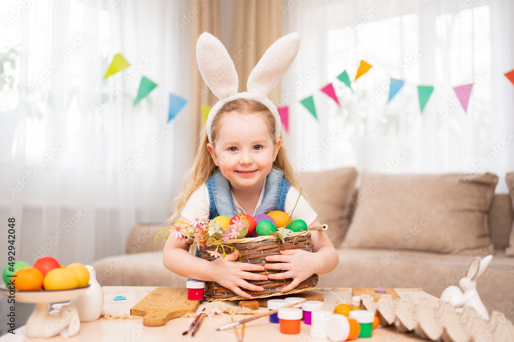 a happy little girl with rabbit ears holds basket with painted eggs a happy little girl with rabbit ears holds basket with painted eggs