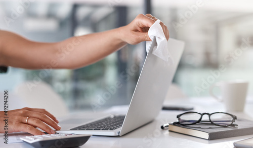 A clean workspace is key. Closeup shot of an unrecognisable businesswoman cleaning a laptop in an office. photo