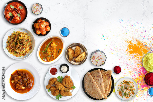 Canvastavla Assorted Indian Holi festival non veg food like Prawns masala, Laddo, Mutton Biryani, Mutton Curry, Fish curry, Fried Chicken, puranpoli, gujiya, gulab jamun with colorful background with copy space