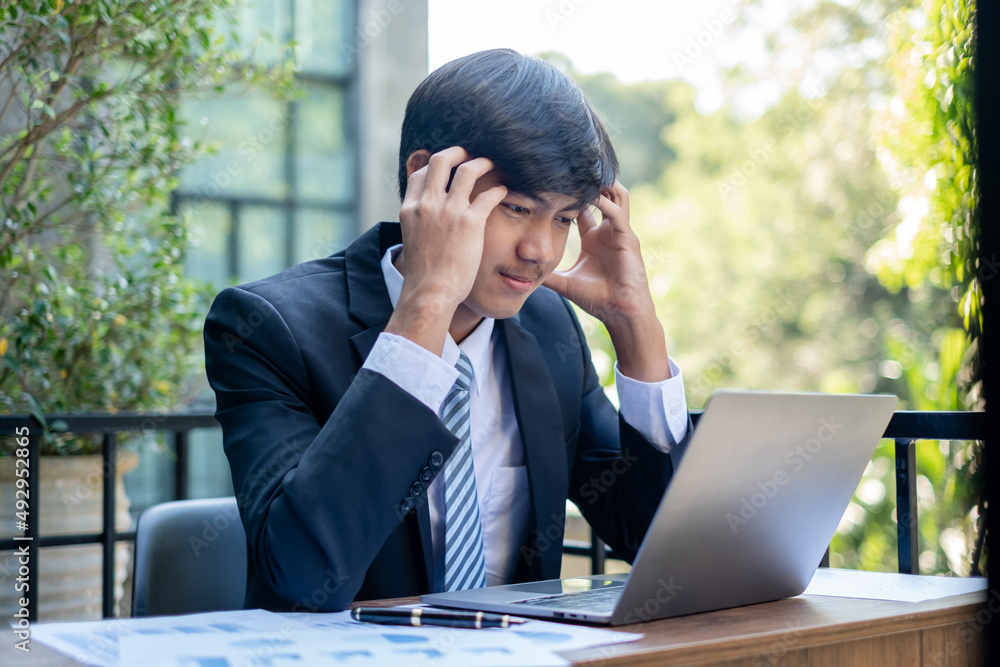 Working Asian men feel stressed, tired from work, migraine headaches from hard work while working at the office Working Asian men feel stressed, tired from work, migraine headaches from hard work while working at the office