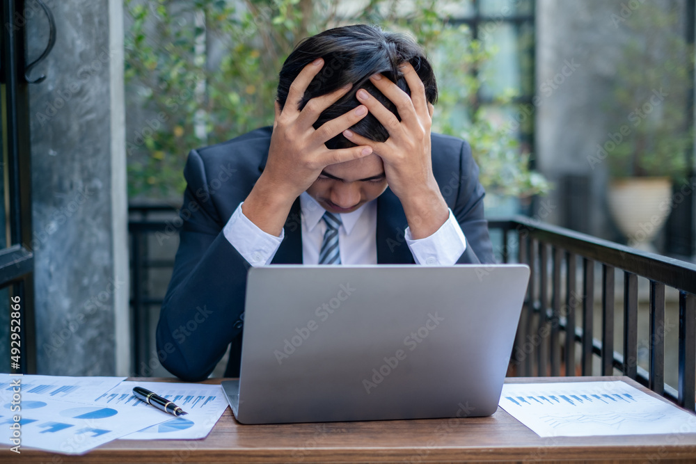 Working Asian men feel stressed, tired from work, migraine headaches from hard work while working at the office Working Asian men feel stressed, tired from work, migraine headaches from hard work while working at the office