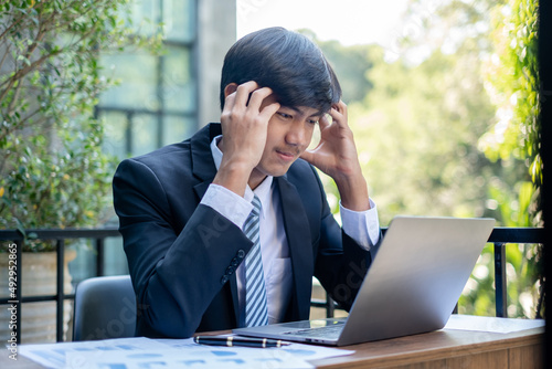 Working Asian men feel stressed, tired from work, migraine headaches from hard work while working at the office