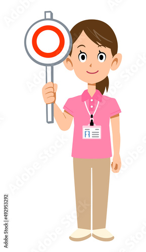 半袖のポロシャツ姿でネームタグを身に着けた女性スタッフの正解の札を掲げる様子
