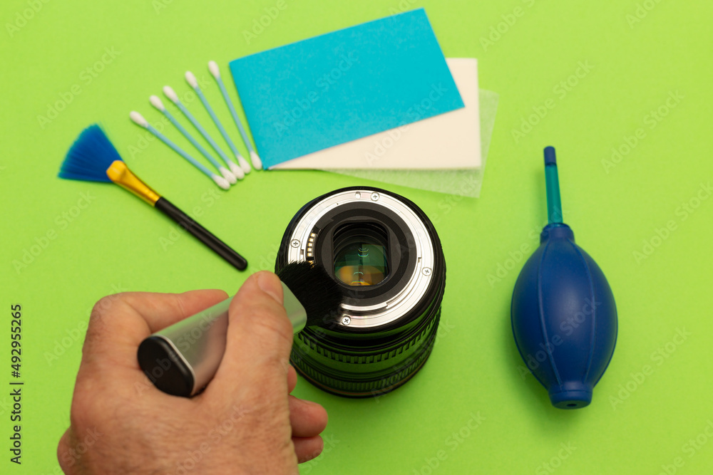 Dslr camera lens, air blower, cotton swab and lens cleaning papers on isolated green background