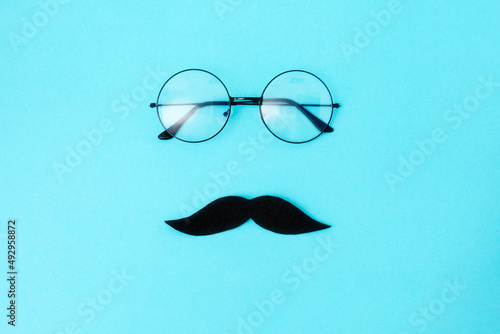 A felt moustache and eyeglasses on blue background with glasses. Top view. Concept of Father's day .