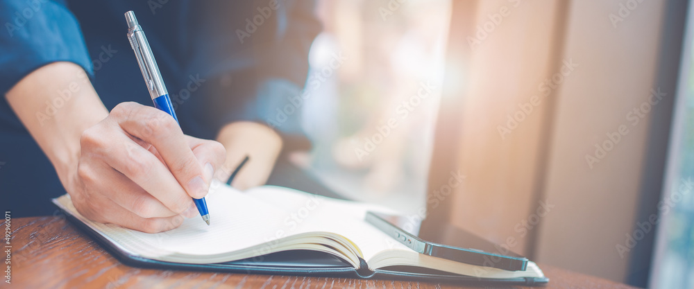 Woman hand writing on a notepad with a pen in the office.