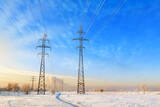 High voltage power lines at sunset. Winter landscape. Metal poles with high electrical load against the blue sky.