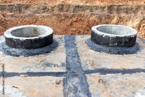 Installation of a reinforced concrete well for water supply and sewerage at the construction site. Well rings with cast iron hatch and construction tool. © Anoo