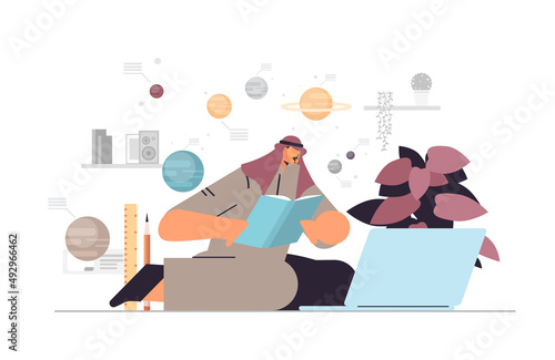 arab man student using digital webinars on laptop and reading book astronomy education or working concept