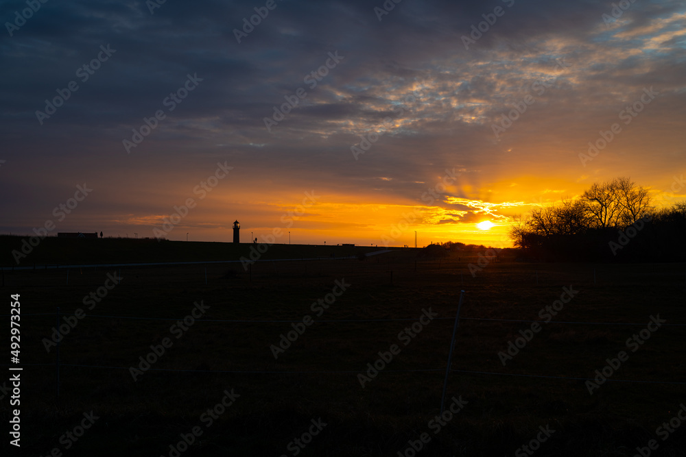 Sunset on the island of Juist with the harbor and lighthouse in the picture Sunset on the island of Juist with the harbor and lighthouse in the picture
