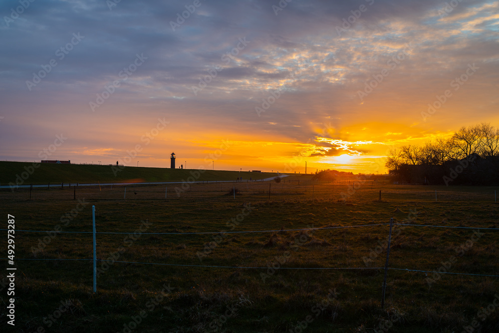 Sunset on the island of Juist with the harbor and lighthouse in the picture Sunset on the island of Juist with the harbor and lighthouse in the picture