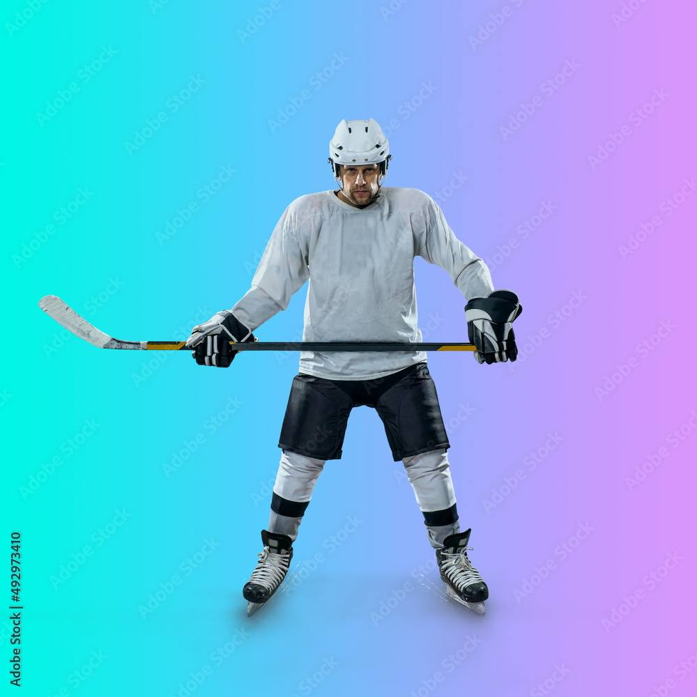 Professional ice hockey player hitting puck for winning goal in action on gradient multicolored neon background. Concept of sport competition.