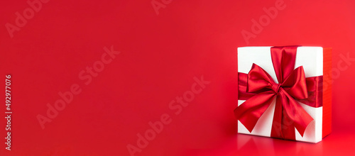  Box with red bow on red background for decoration. Promotional template. Holiday concept. Creative modern design.
