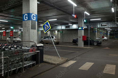 Shopping underground parking lot with an inclined pedestrian crossing sign