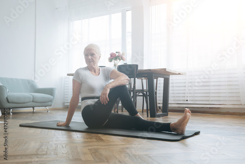 elderly woman sitting on a sports mat in her living room