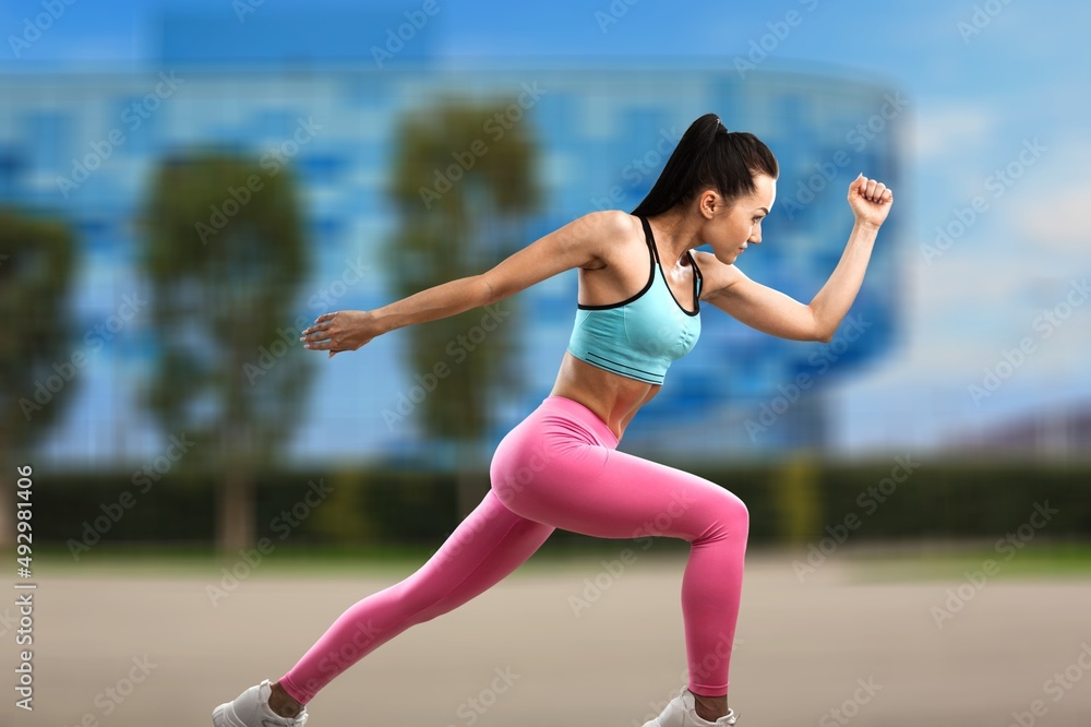 Fototapeta premium Happy fitness woman outdoors. Athletic girl wearing sportswear posing