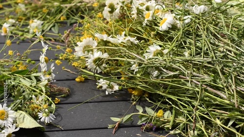 Close-up of homemade flower crown and wild flowers on outdoor table. Tradition to create this beauty and hair accessory for Midsummer celebration in Sweden.