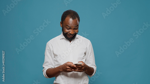 Millennial worker using social media app to text messages on smartphone, talking on online sms chat. Young adult browsing internet and typing on mobile phone touchscreen. Wireless network