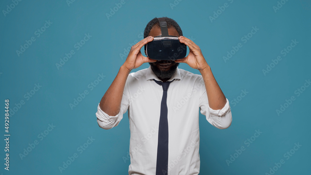 Young man wearing virtual reality glasses in front of camera, enjoying visual 3d simulation experience. Businessman using vr headset to play with innovative tech and futuristic vision. Young man wearing virtual reality glasses in front of camera, enjoying visual 3d simulation experience. Businessman using vr headset to play with innovative tech and futuristic vision.