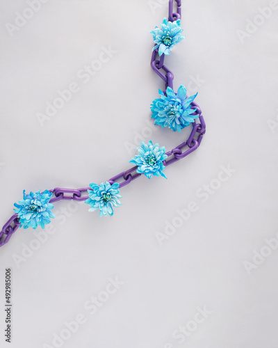 Fresh blue flowers coming out of chain. Spring awakening concept design. Copy space aesthetic flat lay