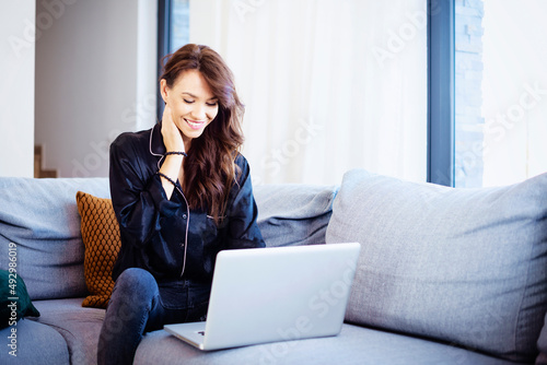Brunette haired attractive woman relaxing at home and using her laptop