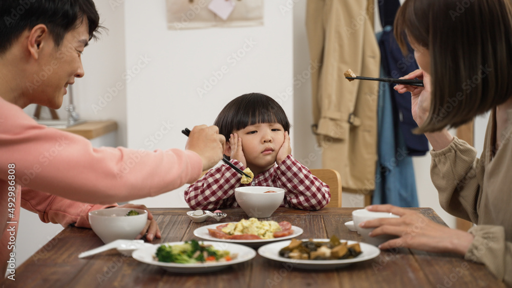 closeup of unhappy Asian preschool boy shaking head and saying no to eat at dining table to his mom and dad at home - obrazy, fototapety, plakaty 