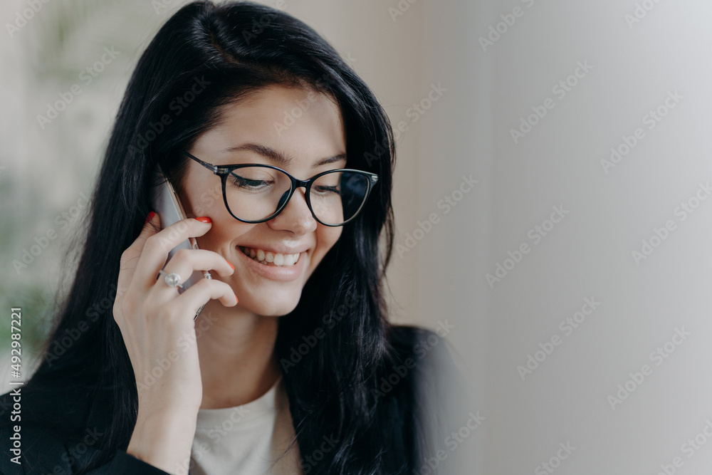 Happy woman lawyer keeps mobile phone near ear, has pleasant conversation with client, discuss working issues Happy woman lawyer keeps mobile phone near ear, has pleasant conversation with client, discuss working issues