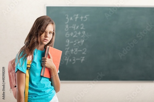 Happy cheerful smiling cute schoolgirl with backpack standing posing in classroom © BillionPhotos.com