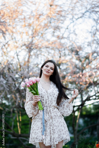 Ukrainian girl in a dress with a bouquet of tulips posing in the park. © Denys