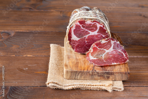 Capocollo of martina franca on wooden table typical from apulia south italy. Italian salami