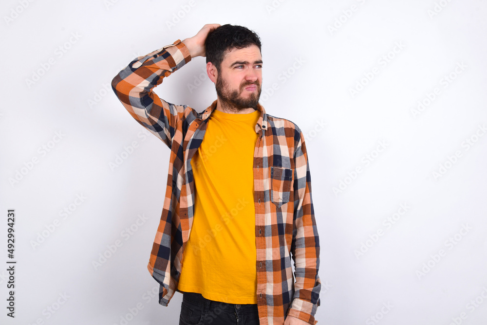 young caucasian man wearing plaid shirt over white background saying: Oops, what did I do? Holding hand on head with frightened and regret expression. young caucasian man wearing plaid shirt over white background saying: Oops, what did I do? Holding hand on head with frightened and regret expression.
