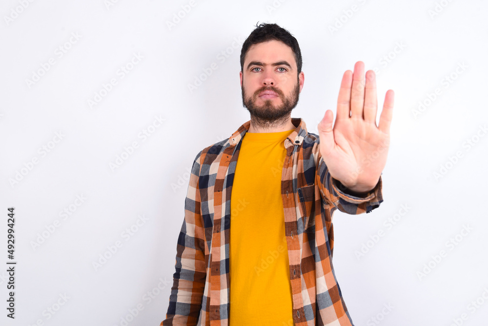 young caucasian man wearing plaid shirt over white background doing stop gesture with palm of the hand. Warning expression with negative and serious gesture on the face. young caucasian man wearing plaid shirt over white background doing stop gesture with palm of the hand. Warning expression with negative and serious gesture on the face.