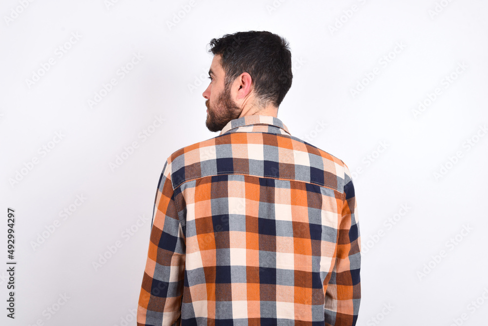 The back view of young caucasian man wearing plaid shirt over white background Studio Shoot. The back view of young caucasian man wearing plaid shirt over white background Studio Shoot.