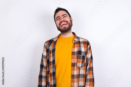 young caucasian man wearing plaid shirt over white background with broad smile, shows white teeth, feeling confident rejoices having day off.