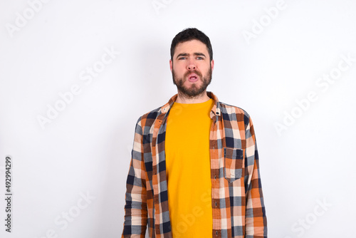 young caucasian man wearing plaid shirt over white background expressing disgust, unwillingness, disregard having tensive look frowning face, looking indignant with something.