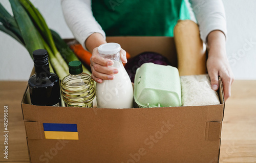 Volunteer preparing food box for ukrainian war refugees - Humanitarian help, donation and aid concept - Soft focus on left hand