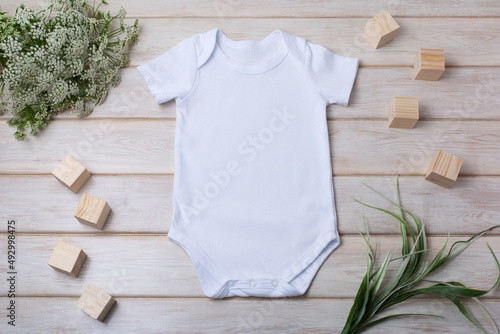 White baby short sleeve bodysuit mockup with green grass and white flowers photo