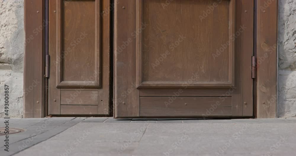 Little child in shorts runs along old city street while ancient building wooden door opens ON summer sunny day extreme close view Little child in shorts runs along old city street while ancient building wooden door opens ON summer sunny day extreme close view