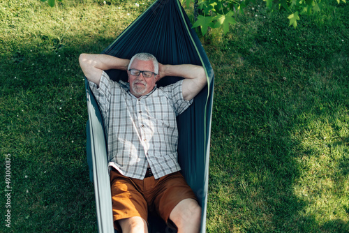 relaxed retired man lying on hammock - senior man on vacation in summer leisure time photo