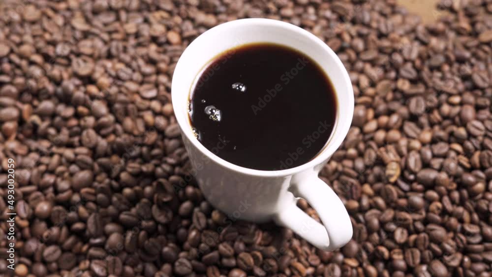 Pour black coffee into a mug from a coffee pot. Pour black coffee into a mug from a coffee pot.