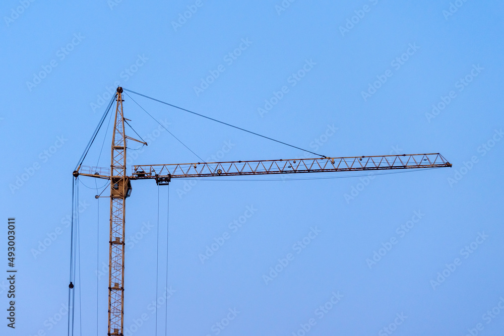 A construction crane on a blue sky background. Copy Space