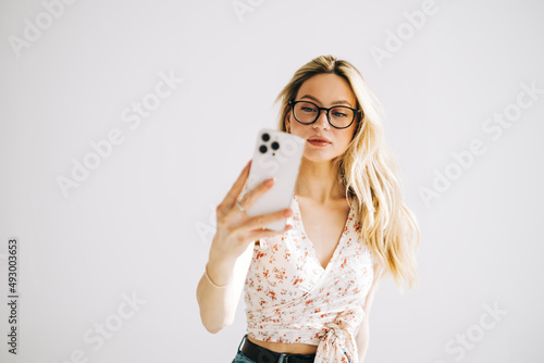 Young attractive caucasian woman in eyeglasses using mobile phone on white background.