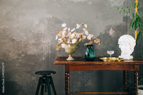 Vintage wooden table with dried bouquet and decoration on black wall background.