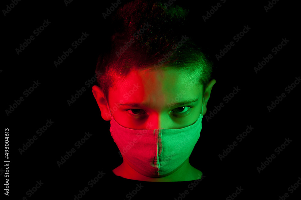 A portrait of the boy wearing in a mask with red and green light making a 3D effect on the dark background A portrait of the boy wearing in a mask with red and green light making a 3D effect on the dark background