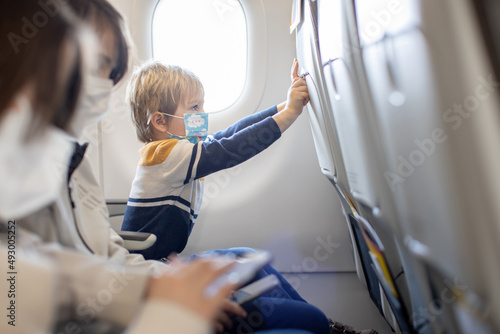Mother and child, boy and mom, sitting in airplane, child playing on tablet #493005252