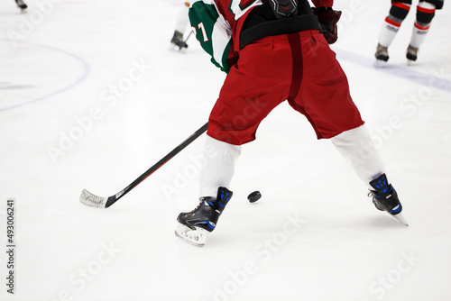 The player during a game of hockey. Close-up of two sticks with a puck while playing on ice