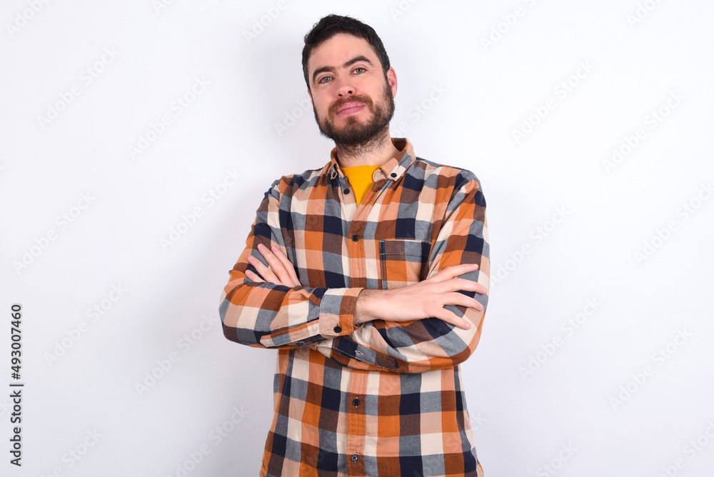Fototapeta premium Confident young caucasian man wearing plaid shirt over white background with arms crossed looking to the camera